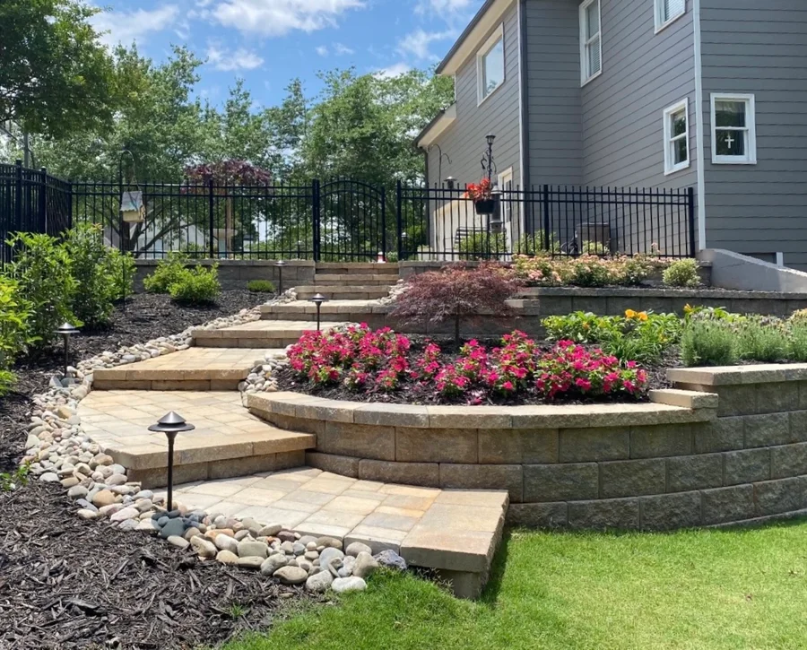 Tiered planting beds with paver steps, river rock, lighting, and colorful plantings