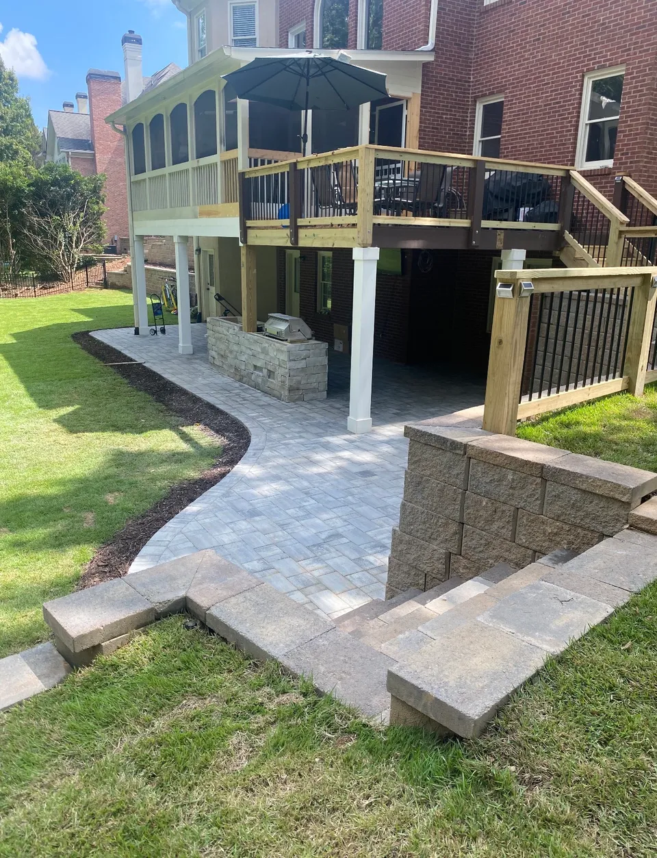 Paver patio, steps, and seat wall beneath a deck