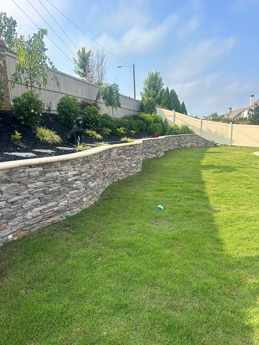 Stone retaining wall with finished lawn and privacy fence